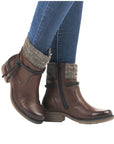 Model wearing brown Rieker 79688 waterproof ankle boots with jeans, showcasing stylish winter-ready design and cozy knit cuff.