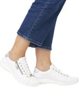 Model wearing the white lace-up sneakers, styled casually with jeans.