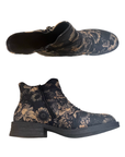 Pair of ankle boots with a dark charcoal gray base and a beige floral pattern, a side zipper on each side and a low block heel.