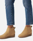 Model wearing tan Women's Sorel Evie Pull On Wedge Boots with jeans, emphasizing the boot's ankle fit and casual waterproof style.