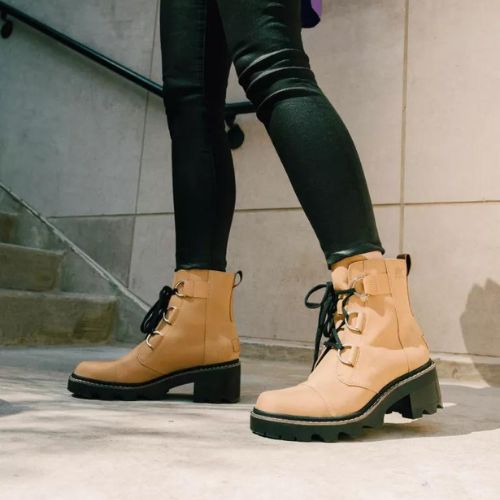 Model wearing Women's Sorel Joan Now Lace Waterproof Boots in tan leather, styled with black skinny jeans for urban fall fashion.