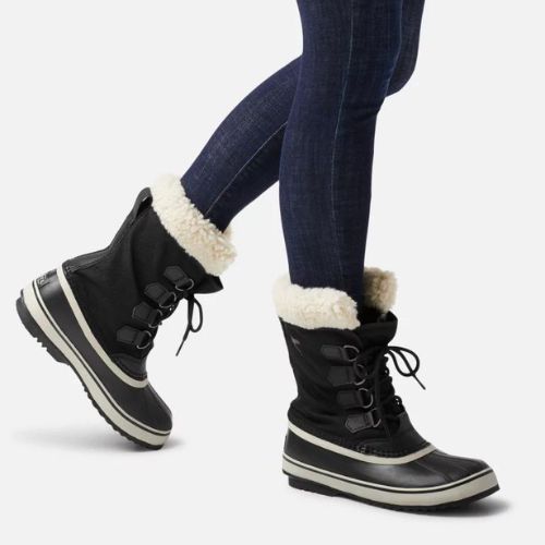Black Women's Sorel Winter Carnival Waterproof Boots styled with jeans, highlighting mid-calf height and warm fleece lining for winter fashion.