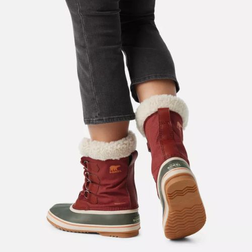 Back view of red Women's Sorel Winter Carnival Waterproof Boots worn with jeans, showcasing cozy fleece lining and rugged winter-ready sole.