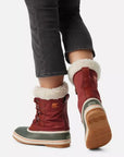Back view of red Women's Sorel Winter Carnival Waterproof Boots worn with jeans, showcasing cozy fleece lining and rugged winter-ready sole.
