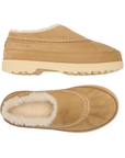 Pair of tan slip-on clog-style shoes with a cream-colored faux shearling lining and a thick cream outsole.