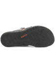Black leaf pattern outsole of slide sandal with orange Taos logo stamped in middle.