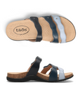 Pair of Slide sandals with wavy straps; black strap, dark blue strap and light blue strap, tan Taos logo'd footbed and black outsole.