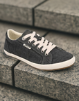 Women's Taos Star Lace-Up Sneaker displayed on stone steps, highlighting stylish design and supportive structure for casual wear.