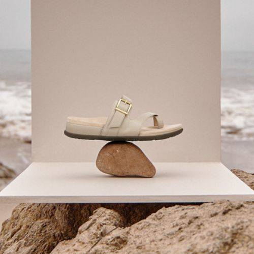 Carmela Toe Loop Sandal displayed on a rock by the beach, showcasing its balance, style, and summer-ready comfort for healthy feet.