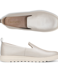 Pair of Slip-on loafers in champagne colored leather with pull tab, tan Vionic logo'd footbed and white lugged outsole.