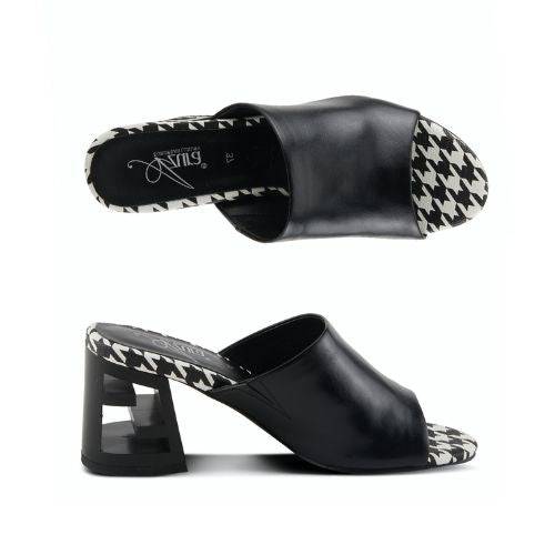 A pair of black open toe leather block heel sandals with a black and white checkered footbed. The block heel has chunky "Z" shaped cut out.