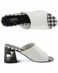 A pair of white open toe leather block heel sandals with black and white checkered footbed. Block heel has chunky "Z" shaped.