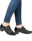 Model wearing black heeled leather shoes with jeans.