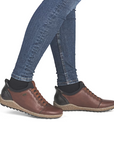 Brown leather shoes worn with blue jeans and black socks.