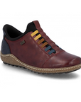 Red leather slip on shoe with navy accents, faux yellow, brown and blue elastic lace details and a treaded black outsole.