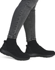 Black slip-on shoes worn with gray jeans.