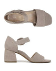 Pair of greyish beige textured leather block heels with square open toe, decorative buckle on velcro ankle strap and a tan Vionic logo'd footbed.