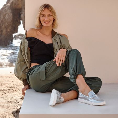 Women wearing silver Leather Loafers sitting casually at a beach.