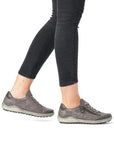 Model wearing grey Remonte R1402 lace-up sneakers with black pants, ideal for stylish and supportive everyday wear.