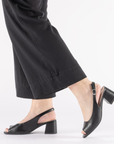 Black open toe slingback heels worn with black pants.