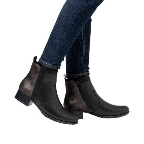 Model wearing black Rieker 78658 ankle boots with jeans, showcasing the boot's sleek leather finish and versatile fall-ready look.