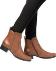 Model wearing brown Rieker 78658 ankle boots with black leggings, highlighting the stylish and versatile fall boot design.