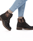 Black lace-up boots worn with light blue jeans and patterned tan socks.
