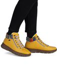 Yellow boots with colorful accents worn with black pants.
