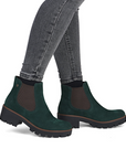 Green Chelsea boots worn with gray jeans.