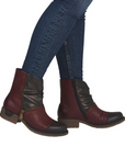 Woman wearing red and bronze ankle boots with accent zipper in blue jeans.