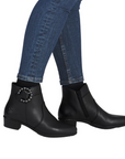 Black ankle boots with decorative beaded buckle worn with blue jeans.