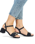 Woman in jeans wearing navy block heel sandals.