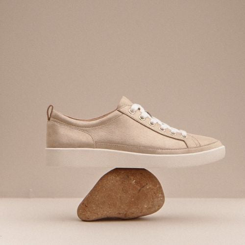 Champagne Winny Sneaker - Leather Lace-Up balanced on a rock. Highlights its lightweight, supportive, and stylish design.