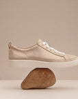 Champagne causal lace Sneaker balanced on a rock.