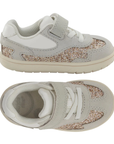 Pair of A toddler's light gray sneakers with a glittery gold and silver side panel, white elastic lacing, and a hook-and-loop strap closure.
