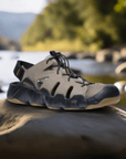 Men's KEEN Hyperport Fisherman Leather Sandal displayed outdoors on a rock by a river, highlighting its rugged, water-ready design and grippy outsole.