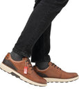 Model wearing brown lace-up leather sneakers, styled with black jeans.
