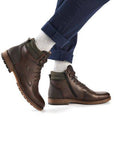 Model wearing brown men's lace-up ankle boots with side zipper, styled with rolled up blue jeans.