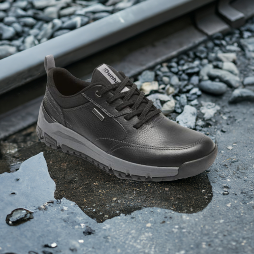 Black Dunham Glastonbury Ubal II Sneaker in wet outdoor setting, highlighting its waterproof leather construction for rugged environments.