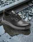Black Dunham Glastonbury Ubal II Sneaker in wet outdoor setting, highlighting its waterproof leather construction for rugged environments.