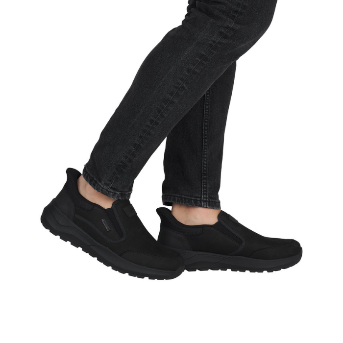 Black slip on sneakers worn with black jean pants.