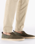 Person wearing green mesh espadrilles with beige pants.