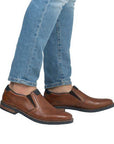 Model wearing brown leather loafers with jeans.