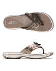 Top and profile view of Bronze thong sandal with white midsole, bronze footbed with white designs including Clarks Cloudsteppers logo, fabric toe post, and adjustable bronze strap with bronze flower. Bronze outsole with rocker bottom design.