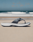 Clarks Breeze Reyna women's sandal in navy displayed on a beach, emphasizing its lightweight build and casual summer style.