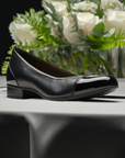 Women's Clarks Juliet Step Flat displayed on a table with floral centerpiece, highlighting its elegant leather finish.