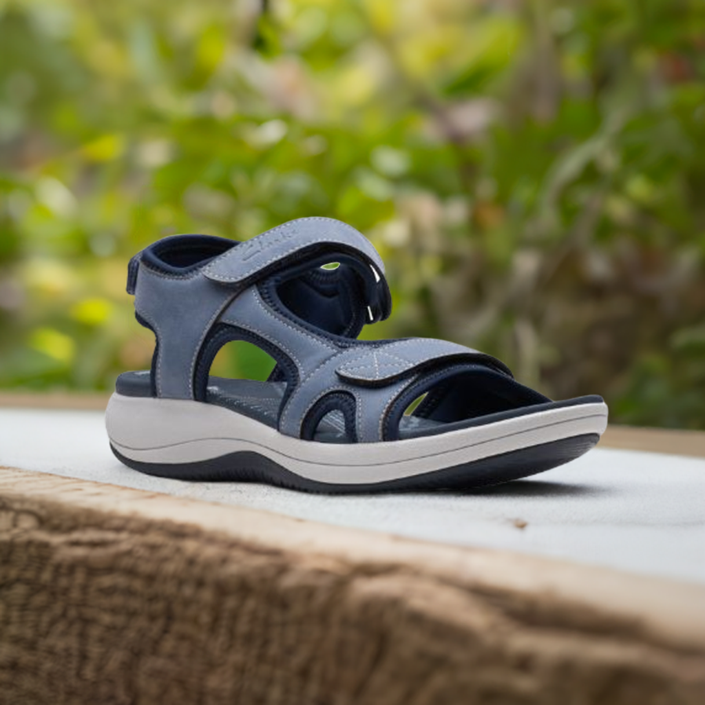 Women's Clarks Mira Bay Sport Sandal in blue displayed outdoors, highlighting its sporty style and breathable design for summer wear.