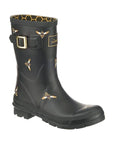 Molly Mid-Height Welly in Black Bees. Black rubber boot with yellow accents and a black outsole. Features a decorative gold buckle. Upper has painted-on yellow bees.