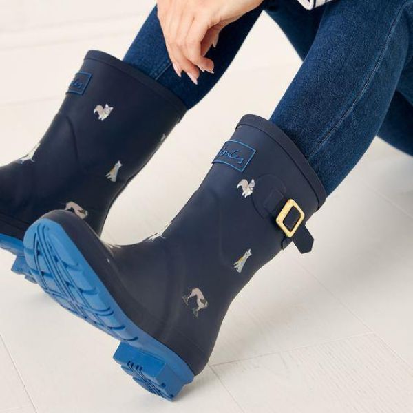 Model in jeans wearing the Molly Wellies in Navy. Grippy outsole is visible.