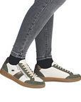 Green and white lace & zipper sneakers worn with gray jeans.